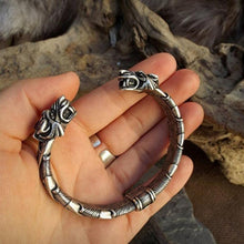 Load image into Gallery viewer, Silver bracelet with dragon design held in a hand against a natural background